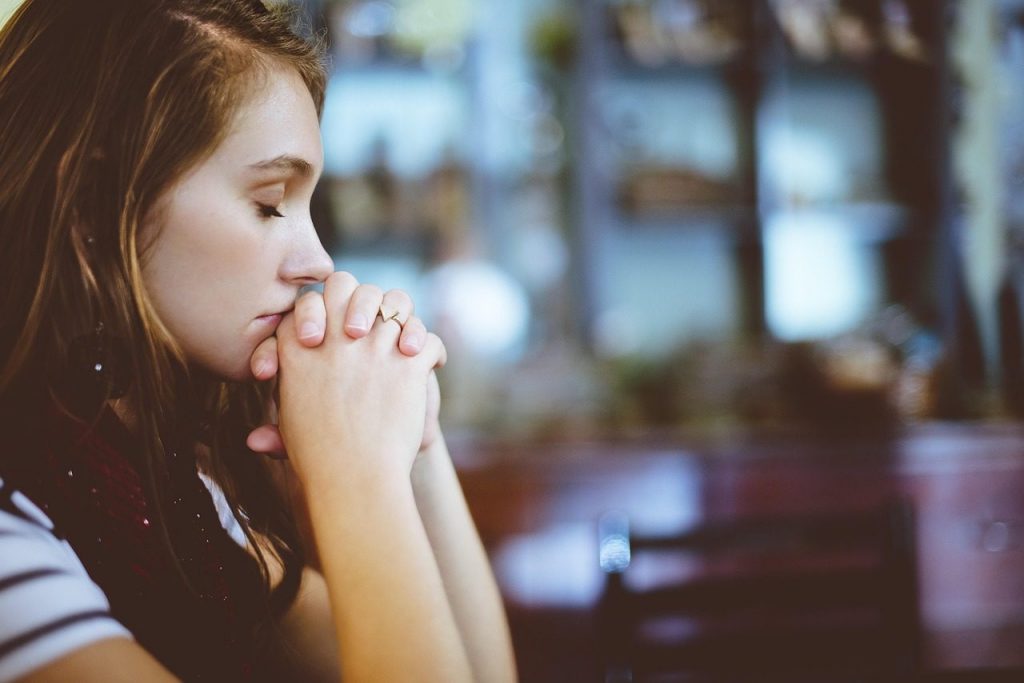 Woman with hands clasped in a prayer pose, representing the connection between spirituality and mental health